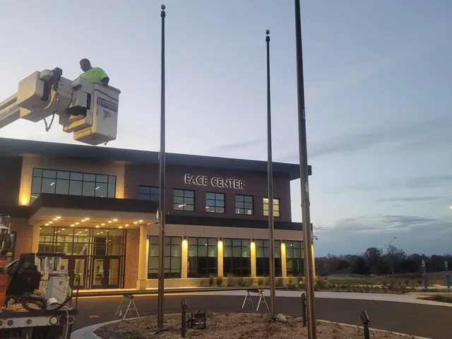 Off Duty Flagpoles crew in a bucket at the top of a commercial flagpole at dusk in Indiana