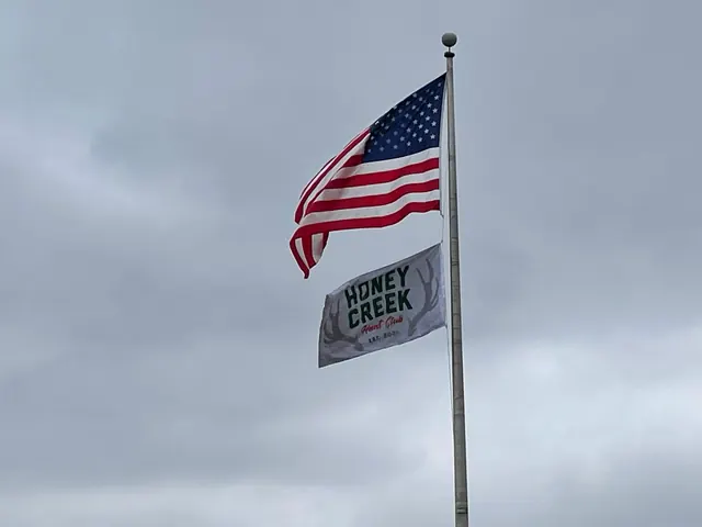 Commercial flagpole flying the national flag and a Honey Creek branded flag in Terre Haute, Indiana